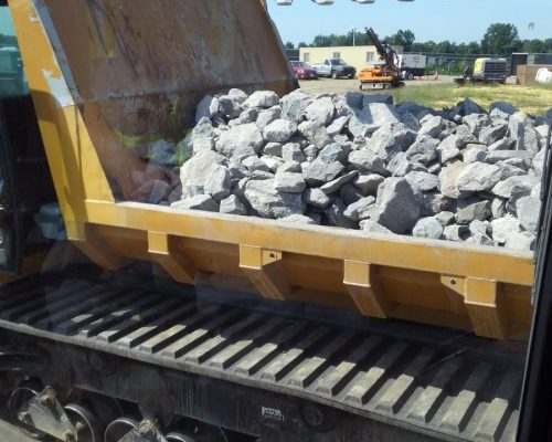 backhoe moving rocks into truck